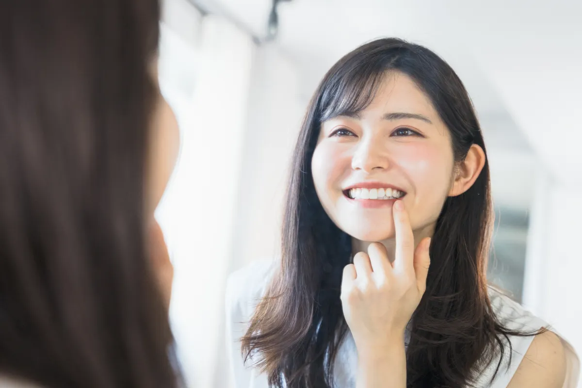 歯の治療後に鏡でチェックする女性